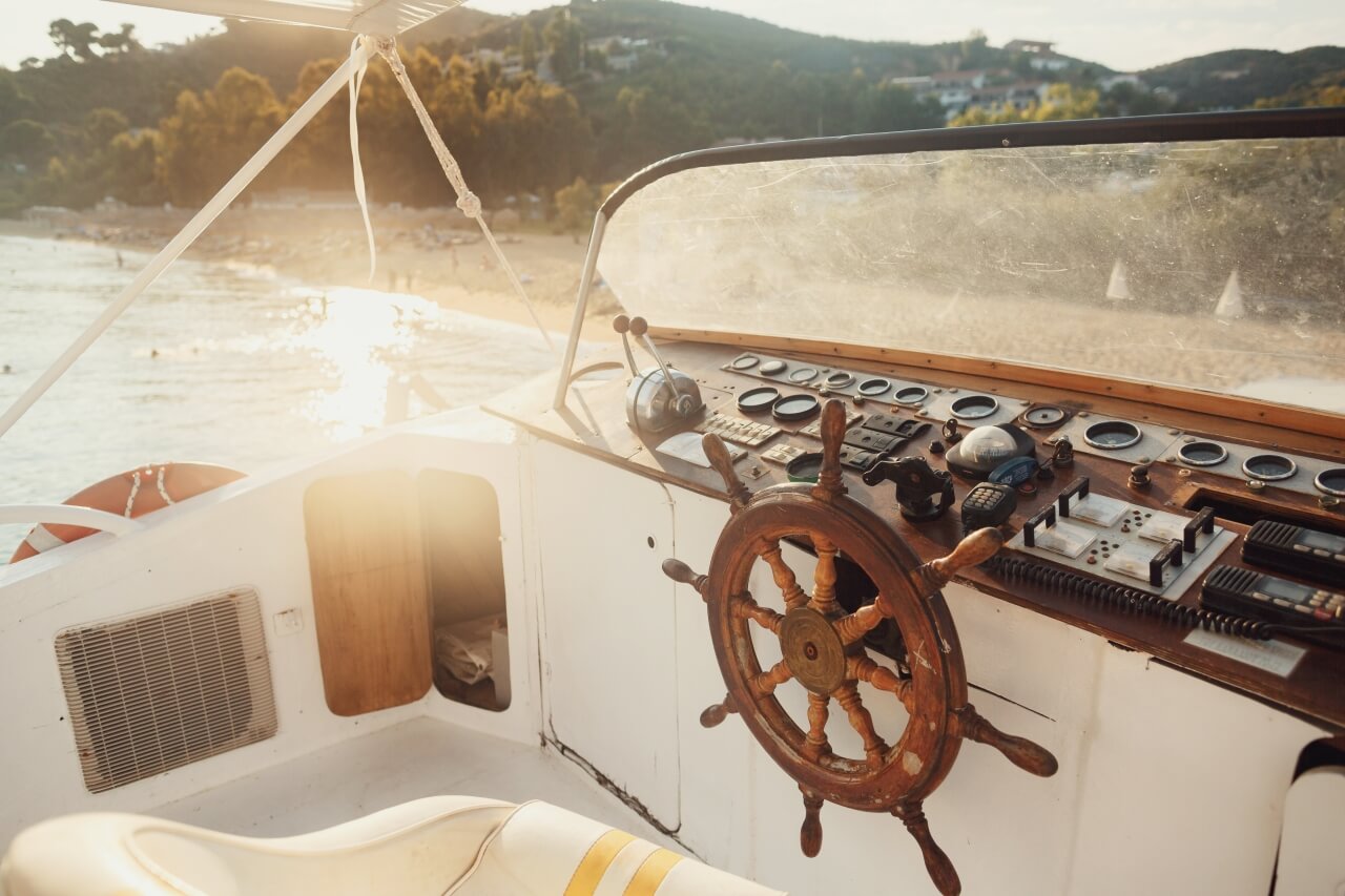 Classic wooden boat steering wheel at sunset - inspiration for boat name generator