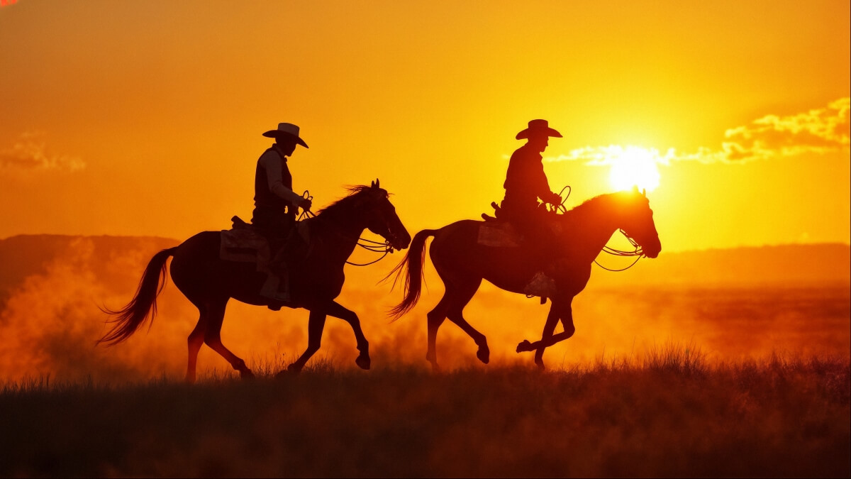 Two cowboys riding horses across the frontier at sunset - authentic inspiration for Wild West cowboy name generation
